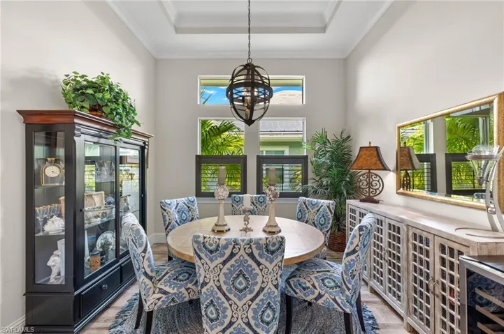 Dining room featuring a raised ceiling, a wealth of natural light, a chandelier, and hardwood / wood-style flooring