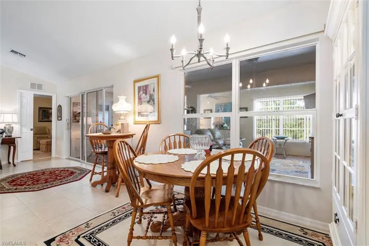 Dining space featuring a notable chandelier, vaulted ceiling, and light tile patterned flooring