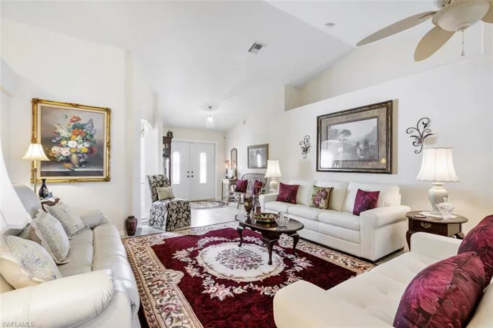 Tiled living room with ceiling fan and vaulted ceiling