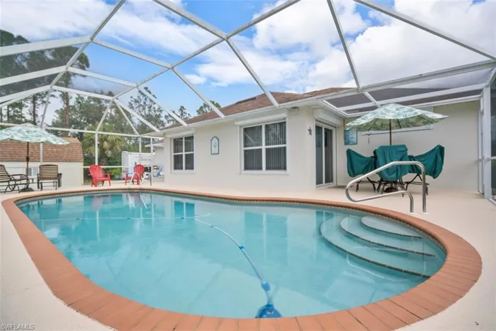 View of pool featuring glass enclosure and a patio