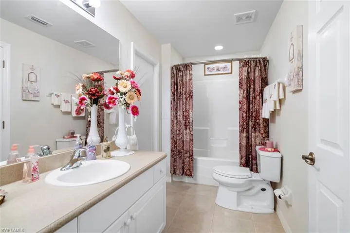 Full bathroom with toilet, tile patterned flooring, shower / bath combo with shower curtain, and vanity