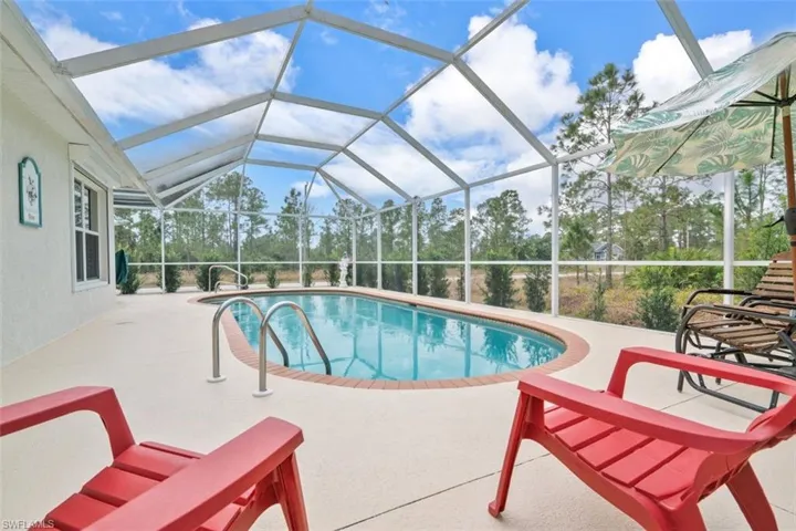 View of swimming pool featuring glass enclosure and a patio area