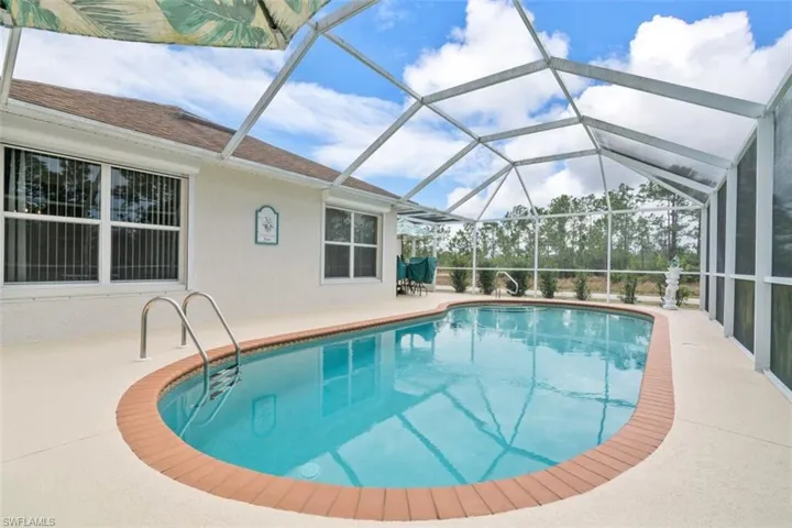 View of swimming pool featuring glass enclosure and a patio area
