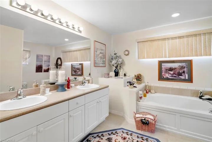 Bathroom with a tub, tile patterned flooring, and double sink vanity