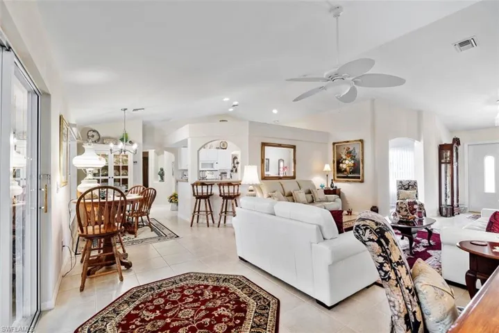 Tiled living room with ceiling fan with notable chandelier