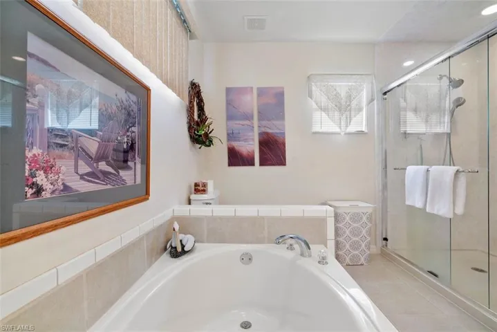 Bathroom with shower with separate bathtub and tile patterned floors