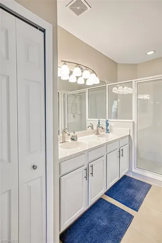 Bathroom featuring tile patterned floors, vanity, and walk in shower