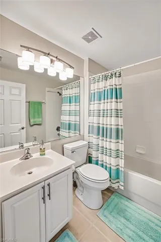 Full bathroom with tile patterned floors, vanity, shower / tub combo, and toilet