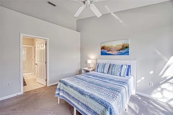Bedroom with light carpet, ensuite bath, and ceiling fan