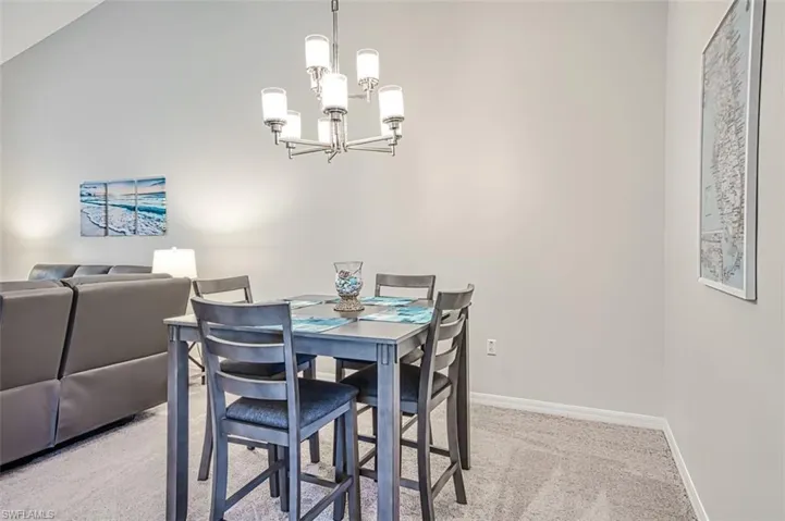 Carpeted dining area featuring vaulted ceiling and a notable chandelier