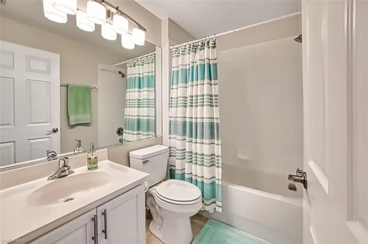 Full bathroom with vanity, toilet, and shower / bathtub combination with curtain