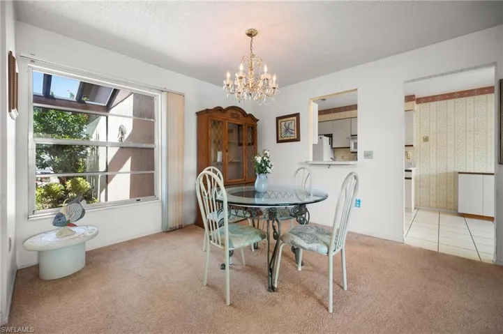 Recessed ceiling with a chandelier, large window with outdoor scenery, built-in display cabinet, and a pass-through window to an additional space