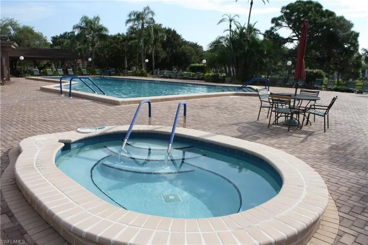 Paved patio with a rectangular swimming pool, an oval hot tub, and integrated handrails