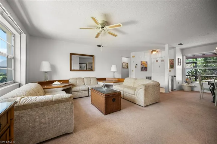 Spacious living area featuring light-toned carpeting and a ceiling fan