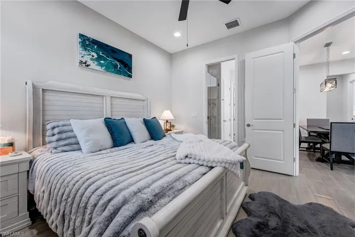 Bedroom with light wood-style floors, a ceiling fan, connected bathroom, and recessed lighting