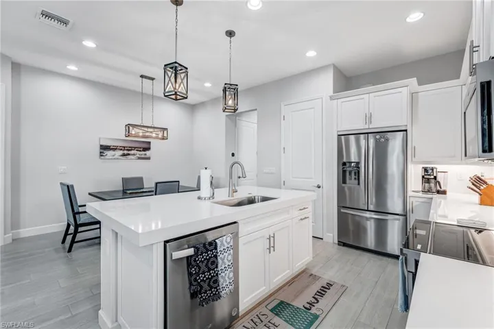 Kitchen with white cabinetry, stainless steel appliances, recessed lighting, pendant lighting, and a kitchen island with sink