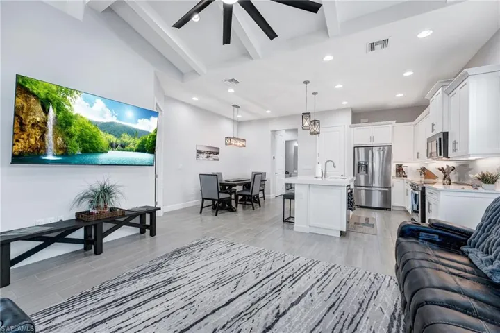 Living room featuring beamed ceiling, light wood-type flooring, recessed lighting, and ceiling fan