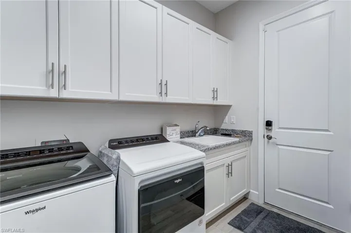Laundry area with washer and dryer, cabinet space, and light wood-style flooring