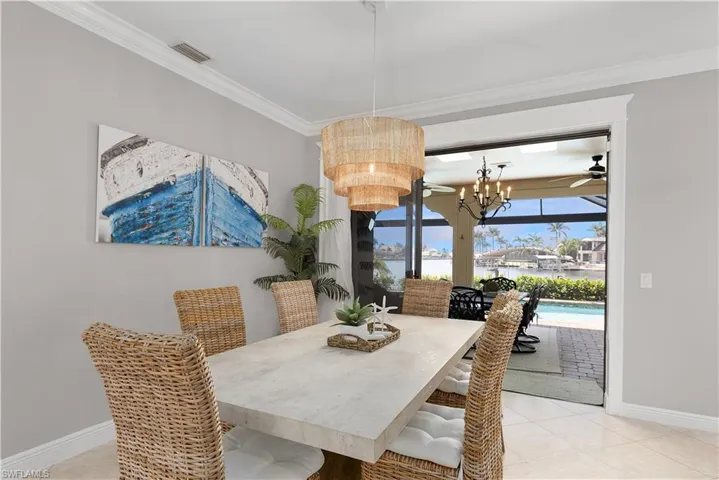Dining space with baseboards, light tile patterned flooring, a sunroom, and a water view