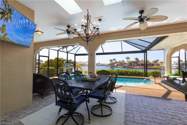 View of patio with a water view, a lanai, an outdoor pool, and ceiling fan