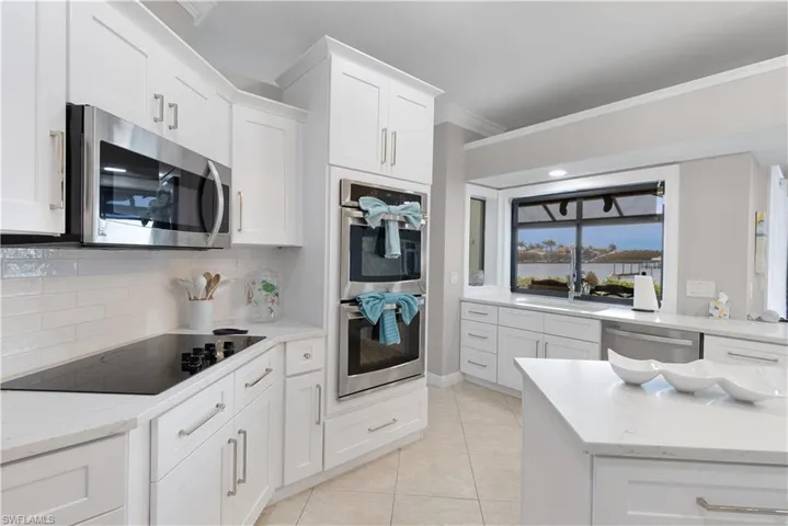 Kitchen with light stone counters, a sink, dishwasher, ornamental molding, and visible vents
