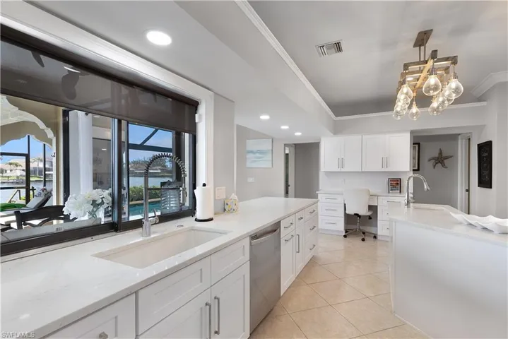 Kitchen with crown molding, tasteful backsplash, a sink, stainless steel appliances, and a center island with sink
