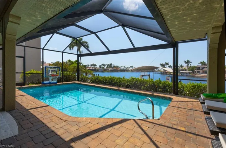 Pool with a patio, glass enclosure, and a water view