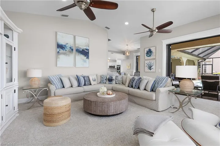 Carpeted living area with vaulted ceiling, visible vents, a ceiling fan, and a healthy amount of sunlight