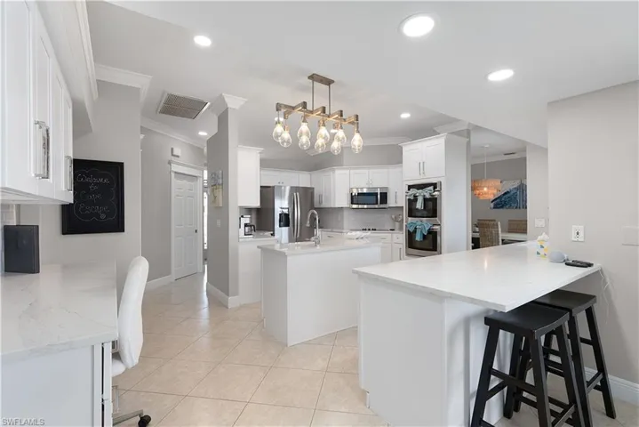 Tiled dining area featuring a water view, crown molding, baseboards, and ceiling fan with notable chandelier