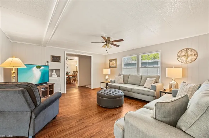 Living room with hardwood / wood-style flooring, ceiling fan, a textured ceiling, and beamed ceiling