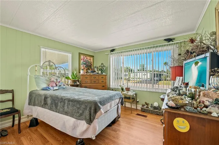 Bedroom featuring a textured ceiling, light wood-type flooring, and crown molding