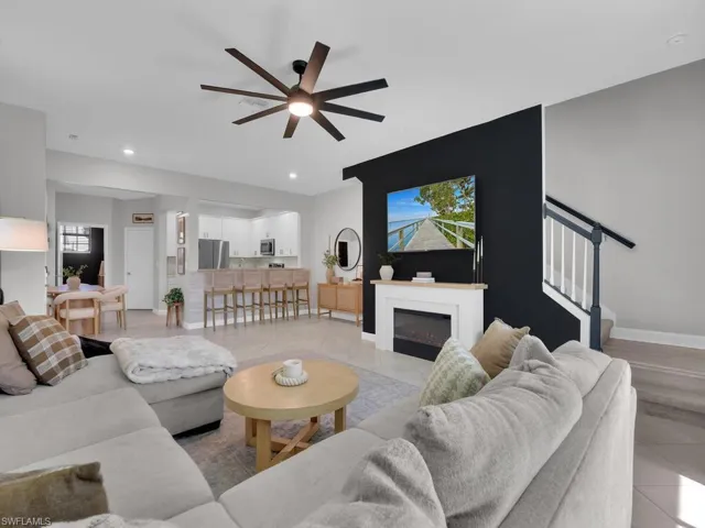 Living area with light tile patterned floors, stairway, ceiling fan, a glass covered fireplace, and recessed lighting