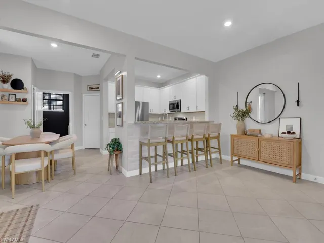 Kitchen with a kitchen breakfast bar, white cabinetry, stainless steel appliances, recessed lighting, and light tile patterned floors