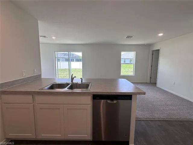 Kitchen with dishwasher, open floor plan, white cabinets, a peninsula, and healthy amount of natural light