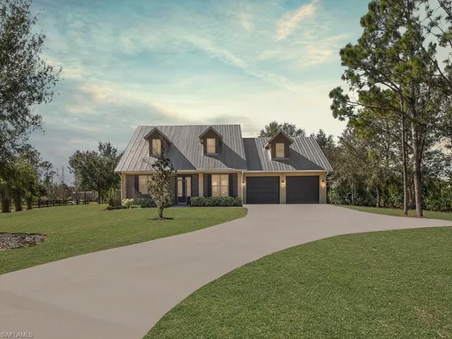 Modern farmhouse featuring a front yard, driveway, a metal roof, and an attached garage
