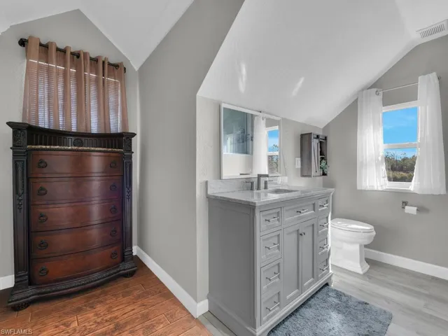 Bathroom with light wood-style flooring, vanity, and lofted ceiling