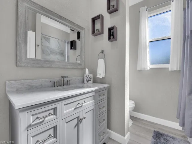 Full bathroom featuring a textured wall, vanity, a shower, and light wood finished floors