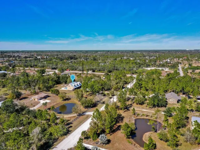 Aerial view of property and surrounding area with a tree filled landscape and a nearby body of water