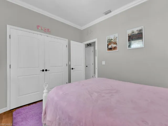 Bedroom featuring a closet, ornamental molding, and wood finished floors
