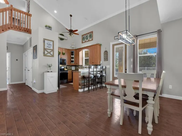 Dining room featuring high vaulted ceiling, ornamental molding, a ceiling fan, and dark wood-type flooring