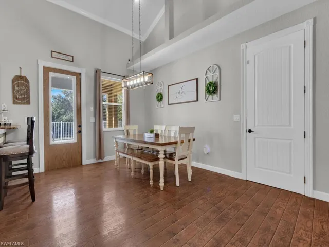 Dining space featuring dark wood-type flooring, ornamental molding, and a towering ceiling