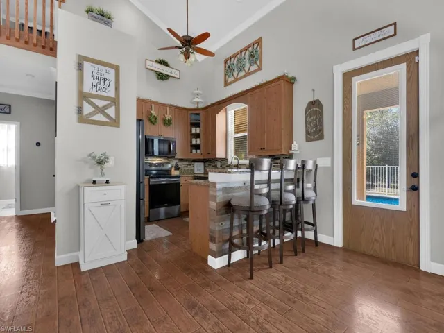 Kitchen featuring brown cabinets, appliances with stainless steel finishes, a breakfast bar, ornamental molding, and a ceiling fan