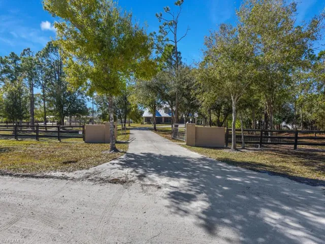 View of asphalt driveway featuring a gated entry and a gate