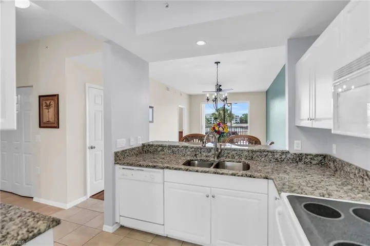 Kitchen featuring white cabinetry, light tile patterned floors, white appliances, and sink