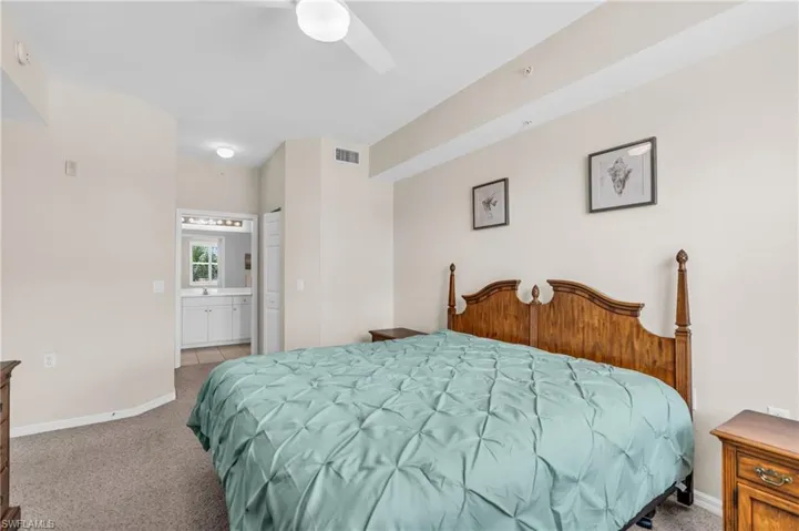Bedroom featuring ceiling fan, sink, light carpet, and ensuite bathroom