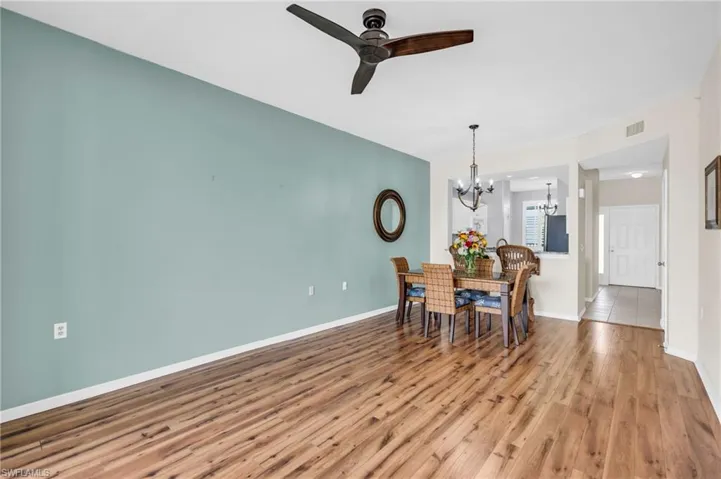 Dining area featuring ceiling fan with notable chandelier and wood-type flooring