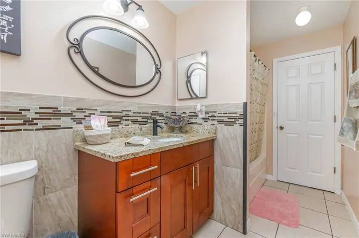 Full bathroom with vanity, shower / tub combo with curtain, and light tile patterned floors