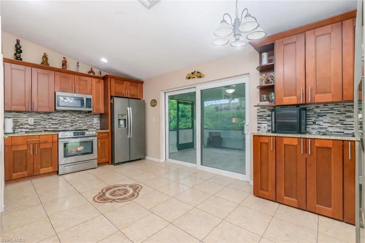 Kitchen featuring decorative backsplash, wood finish cabinetry, stainless steel appliances, light stone counters, and open shelves
