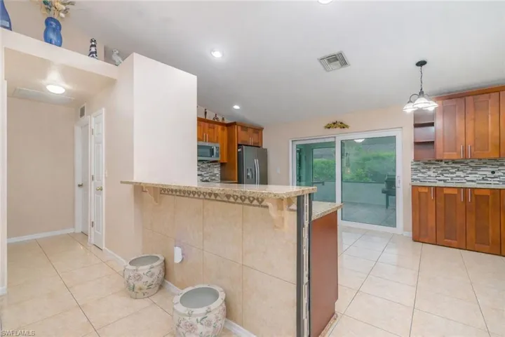 Kitchen featuring wood finish cabinetry, tasteful backsplash, vaulted ceiling, a breakfast bar area, and stainless steel appliances