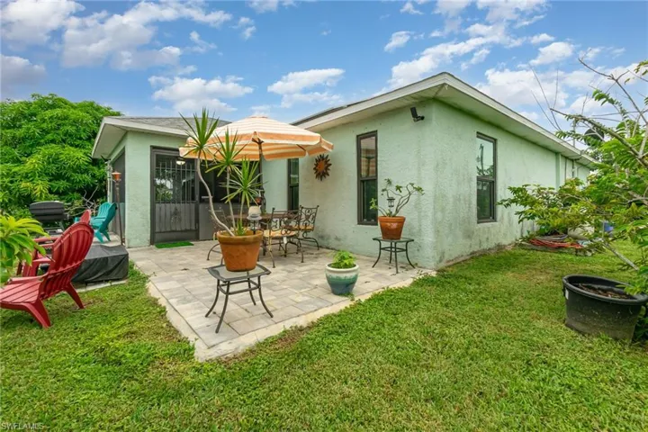 Back of house with stucco siding, a patio area, and a lawn
